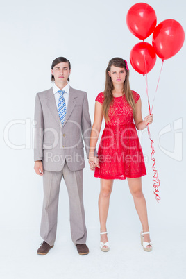 Unsmiling geeky couple standing hand in hand
