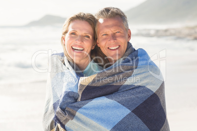 Happy couple wrapped up in blanket