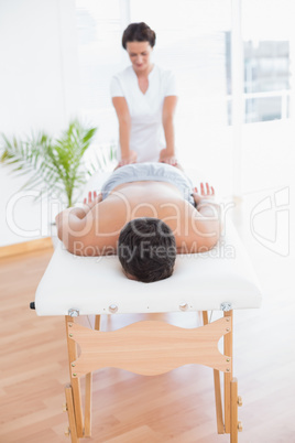 Patient relaxing on the massage table with physiotherapist behin