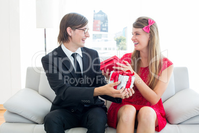 Cute geeky couple smiling and offering gift
