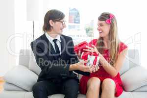 Cute geeky couple smiling and offering gift