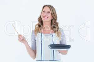 Smiling woman holding frying pan and wooden spoon