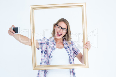 Pretty geeky hipster taking selfie with smartphone