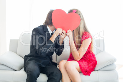 Cute geeky couple kissing and holding heart over faces