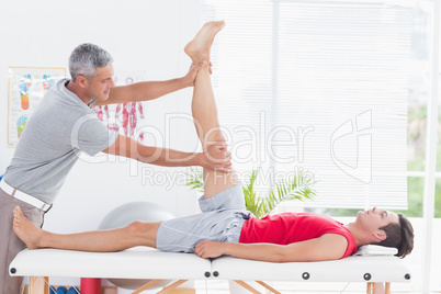 Physiotherapist doing leg stretching to his patient