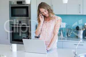 Pretty blonde on the phone using laptop