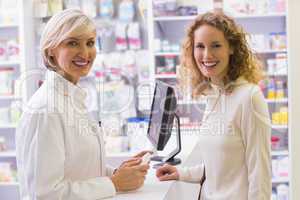 Pharmacist and costumer smiling at camera