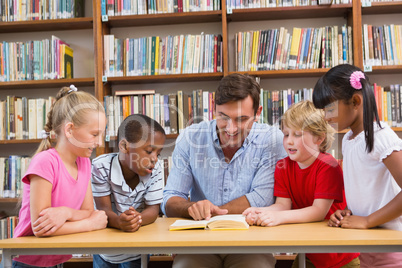 Teacher reading book to pupils at library