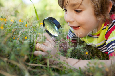 Happy little boy looking through magnifying glass