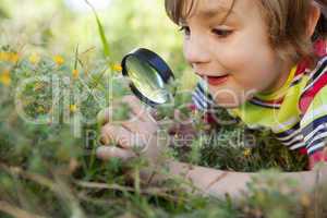Happy little boy looking through magnifying glass