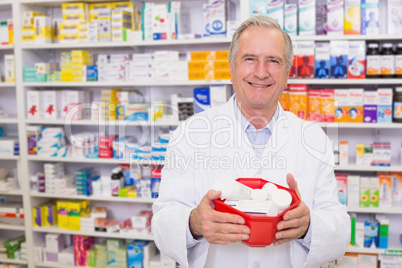Senior pharmacist holding bowl of medicines