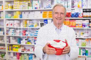 Senior pharmacist holding bowl of medicines