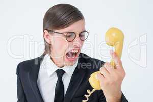 Geeky businessman shouting at retro phone