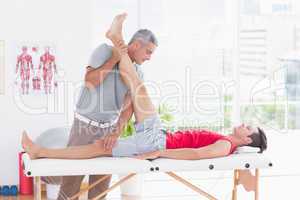 Physiotherapist doing leg stretching to his patient