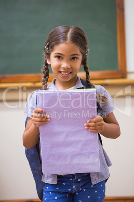 Cute pupil smiling at camera holding notepad