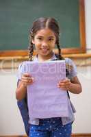 Cute pupil smiling at camera holding notepad