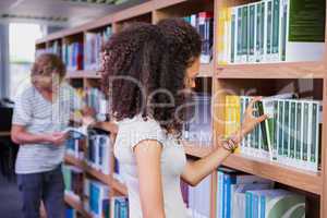 Student picking a book from shelf in library