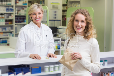 Pharmacist and costumer smiling a camera