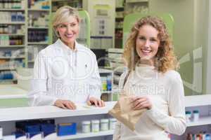 Pharmacist and costumer smiling a camera