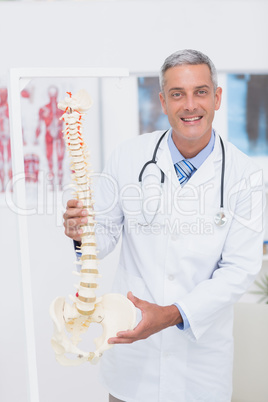 Happy doctor showing anatomical spine