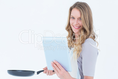 Smiling woman holding frying pan and tablet pc