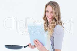 Smiling woman holding frying pan and tablet pc