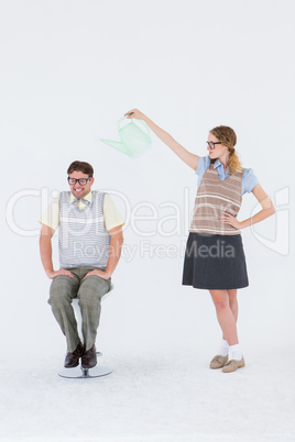 Geeky hipster holding watering can above her boyfriend