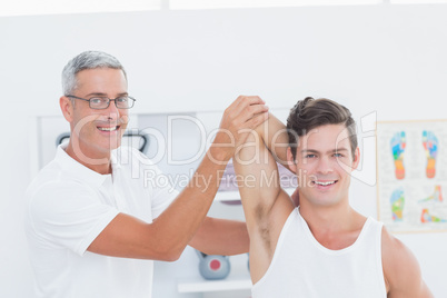 Doctor stretching a young man arm