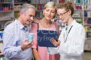 Pharmacist showing clipboard to costumers