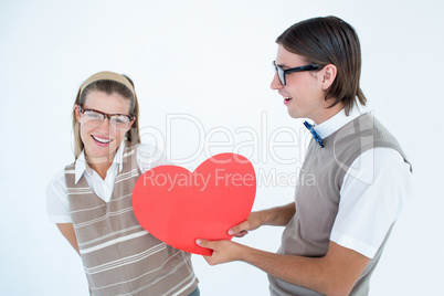 Geeky hipster offering red heart to his girlfriend