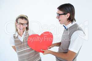 Geeky hipster offering red heart to his girlfriend