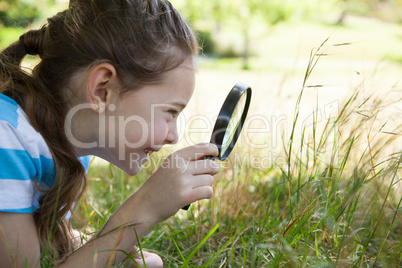 Cute little girl looking through magnifying glass