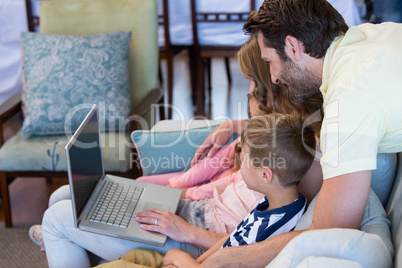 Happy family on the couch together using laptop