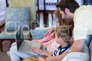 Happy family on the couch together using laptop