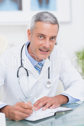 Doctor writing on diary at his desk