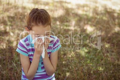 Cute little girl blowing her nose in park