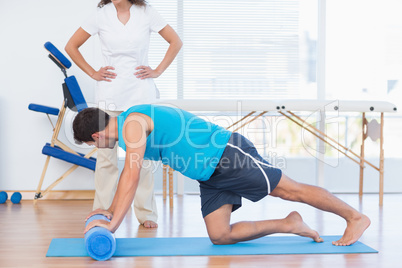 Trainer working with man on exercise mat
