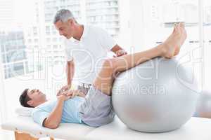 Therapist helping his patient with exercise ball