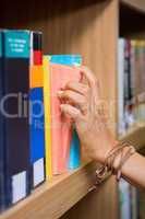 Student picking a book from shelf in library