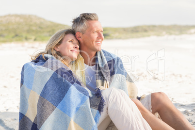 Happy couple wrapped up in blanket