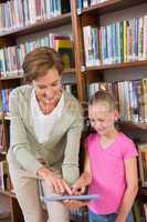 Teacher showing tablet to pupil at library