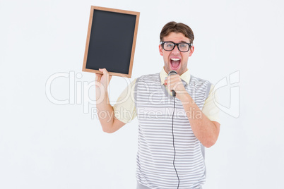 Geeky hipster holding blackboard and singing into microphone