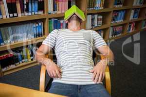 Student asleep in the library with book on his face
