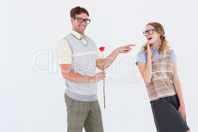 Geeky hipster holding rose and pointing his girlfriend