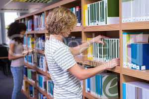 Student picking a book from shelf in library