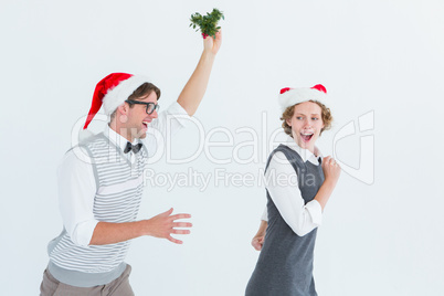 Geeky hipster running away from a man with mistletoe
