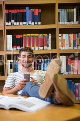 Student listening music in the library with smartphone