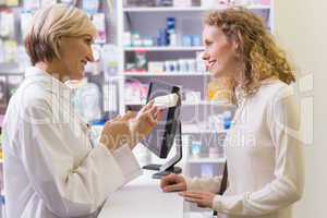 Pharmacist holding medicine box talking to customer