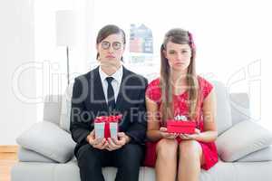Unsmiling geeky couple with gift