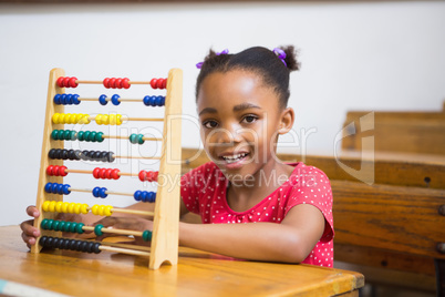 Smiling pupil using abacus in classroom